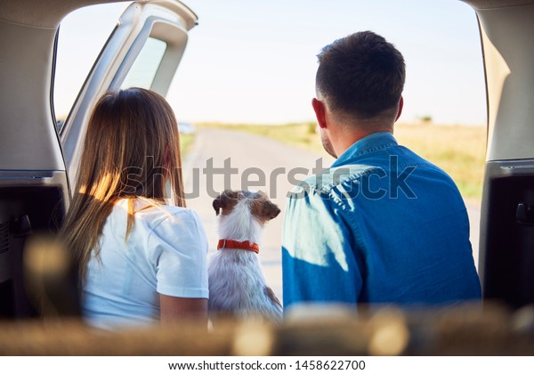 Rear view\
of young couple and dog enjoying the view\
