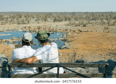 Rear view of young couple observing animals in African savannah - travel concept - Powered by Shutterstock