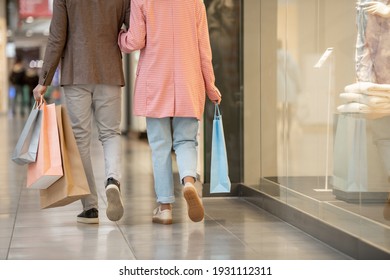 Vista trasera de una pareja joven con bolsas de compras caminando por el centro comercial