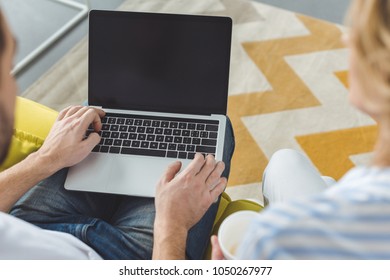 Rear View Of Young Couple Sitting With Laptop With Blank Screen