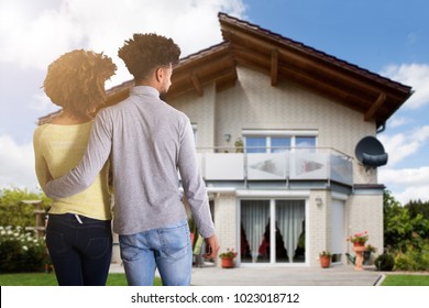 Rear View Of A Young Couple Standing In Front Of House