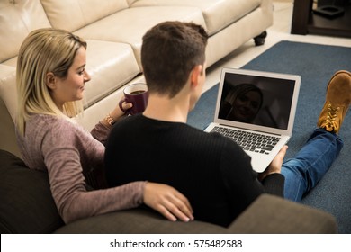 Rear View Of A Young Couple Watching A TV Show On A Laptop Computer At Home