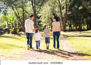 rear view of young family walking in forest 
