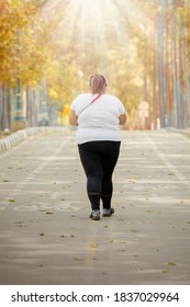 Rear View Of Young Fat Woman Walking On The Road With Autumn Season Background