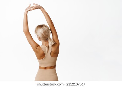 Rear View Of Young Fit Girl Athlete Stretching Arms, Showing Back Muscles, Workout On Fitness Class, Doing Yoga In Activewear, Standing Over White Background