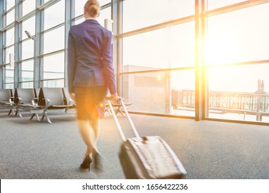 Rear View Of Young Flight Attendant Walking In Airport With Lens Flare