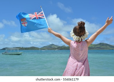 Rear View Of A Young Foreign Tourist Girl On Family Travel Holiday Vacation In Fiji Islands Waving The National Flag Of The Republic Of Fiji. Real. People Copy Space.