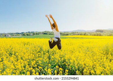 Rear view of a a young homosexual boy jumps in a yellow rapeseed field. Concept of a good mood and summer vacation. Copy space. - Shutterstock ID 2155294841
