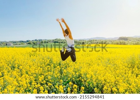 Rear view of a a young homosexual boy jumps in a yellow rapeseed field. Concept of a good mood and summer vacation. Copy space.