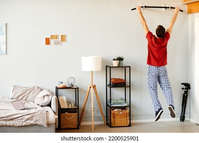 Rear View Of Young Man Doing Exercises On Bar During Sport Training In The Morning At Home