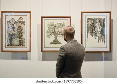 Rear View Of Young Man In Suit Looking At Modern Art On The Wall In Museum