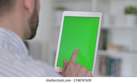 Rear View of Young Man using Tablet with Chroma Key Screen 