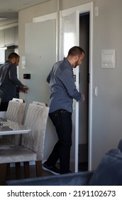 Rear View Of Young Man Walking Out Of His Apartment, Casual Guy Standing Opening The Door.