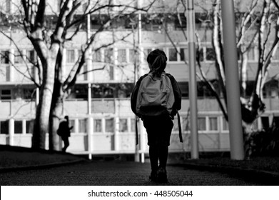 Rear View Of Young School Girl Carry A School Bag Walking Alone  By Herself To School In Urban City Street. Education Concept. Real People.  Copy Space