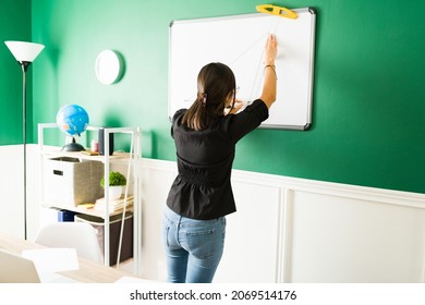 Rear View Of A Young Teacher Writing On A Blackboard And Teaching A Math Class During A Virtual Class 