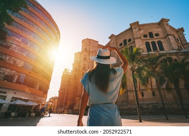Rear view of young tourist woman in white sun hat walking in Malaga city at sunset. Summer holiday vacation in Spain - Shutterstock ID 2052922571