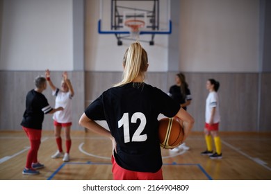 A Rear View Of Young Woman Basketball Player In Gym During Match.