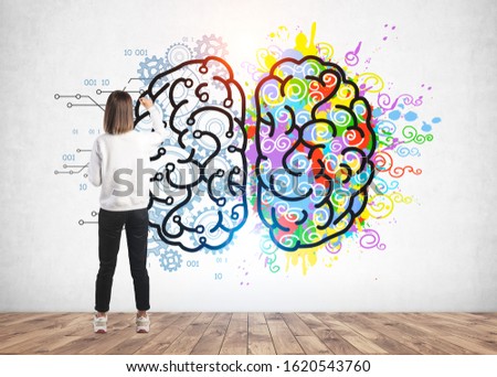Rear view of young woman in casual clothes drawing colorful creative and analytical brain sketch on concrete wall. Concept of education
