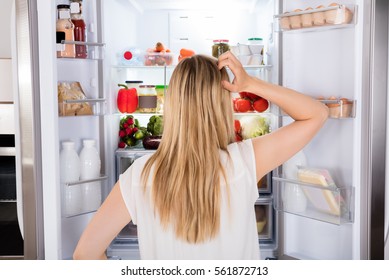 Rear View Of Young Woman Looking In Fridge At Kitchen