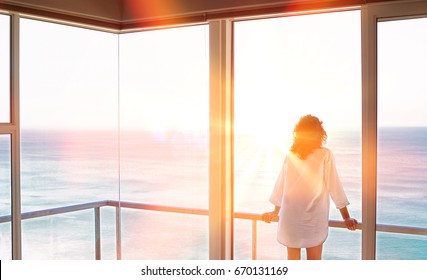 Rear view of young woman looking at sea view from balcony at resort
