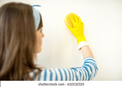 Rear View Or Young Woman In Rubber Glove Cleaning Wall With Sponge