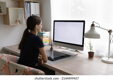 Rear view young woman sit at workplace desk with digital graphic tablet, staring at computer white mock up screen looks interested working or learns professional photo or video editor program concept - Powered by Shutterstock