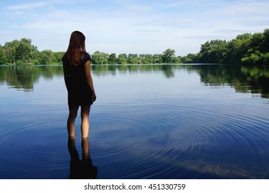 Rear View Of Young Woman Standing In Lake In Solitude
