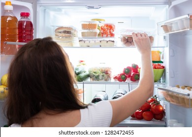 Rear View Of A Young Woman Taking Food From Refrigerator - Shutterstock ID 1282472455