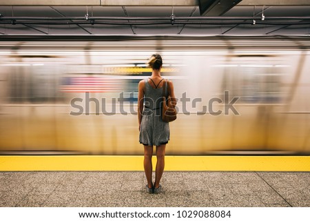 Rear view at young woman waiting for subway train in New York City, USA