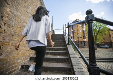 Rear view of young woman walking up stairs outdoors