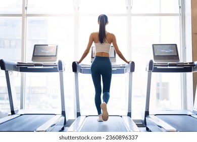 Rear view of young woman walking on treadmill - Powered by Shutterstock