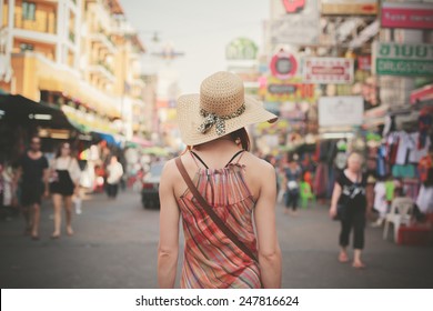 Rear View Of A Young Woman Walking The Famous Backpacker Street Khao San In Bangkok, Thailand