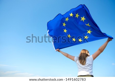 Rear view of young woman waving the European Union flag
