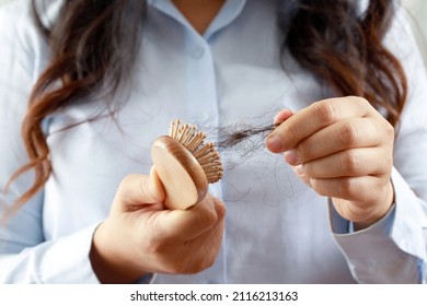 Rear view young woman worried about Hair loss problem, hormonal disbalance, stress concept. Many hair fall after combing in hair brush in hand. Female untangled her hair with a comb, Health care - Shutterstock ID 2116213163