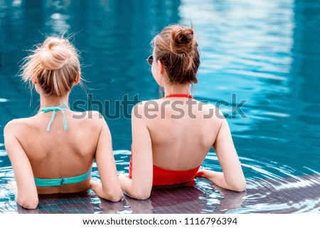 rear view of young women sitting in swimming pool
