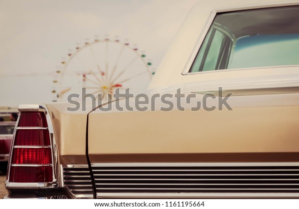 Rear of a vintage car and a ferris wheel\
around background
