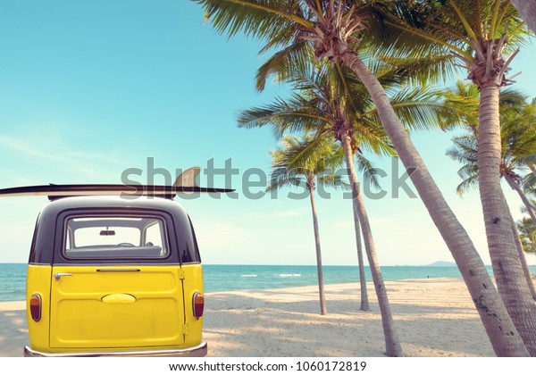 Rear of vintage car parked on the tropical beach\
(seaside) with a surfboard on the roof - Leisure trip in the\
summer. retro color effect