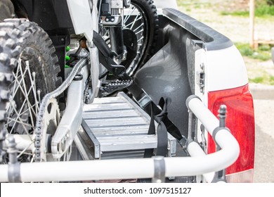 Rear Viwe With Two Dirt Bike Motorcycles On The Back Of The Truck With Safety Gear In Residential Setting.