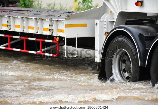 The rear\
wheels of flat bed truck were draining rainwater out of the wheels\
and passing the road in flood\
situation.