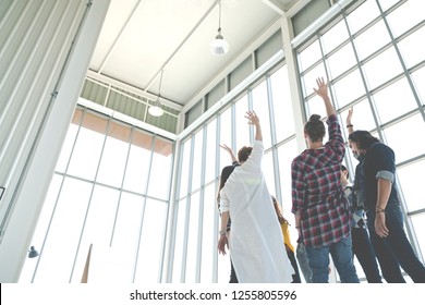 Rear Wide View Of Multiethnic Diverse Creative Asian Group Huddle And High Five Together In Office Workshop With Success Or Empower Expression In Teamwork. Young Asian Marketing Team With Copy Space.