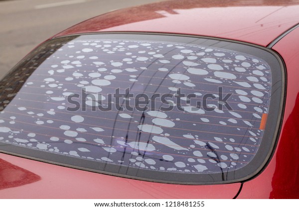 The rear window of a car with a very poor\
substandard tint. Defective rear window tinted red car. Bubbles\
when tinting auto glass. The poor work of the car tinting master.\
Bubbles on glass.
