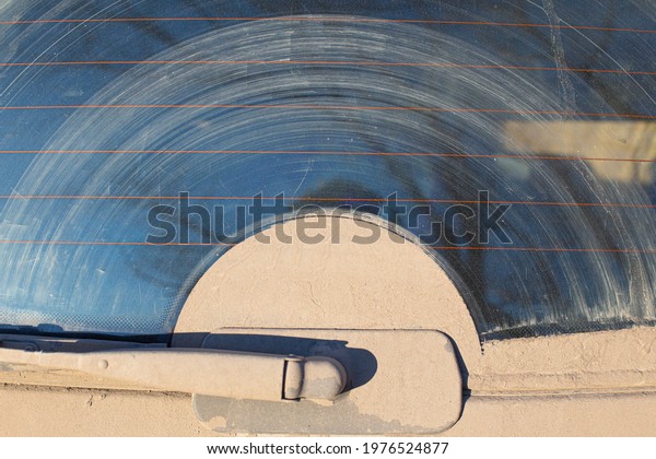 rear\
windshield cleaner of a car, poorly cleaning dirt and dust\
contributing to dangerous driving on a country road, the front and\
background background is blurred with a bokeh\
effect