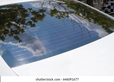 Rear windshields of a white car reflected the beautiful blue sky