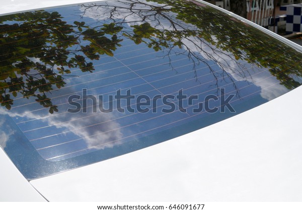 Rear windshields of a white car reflected the\
beautiful blue sky