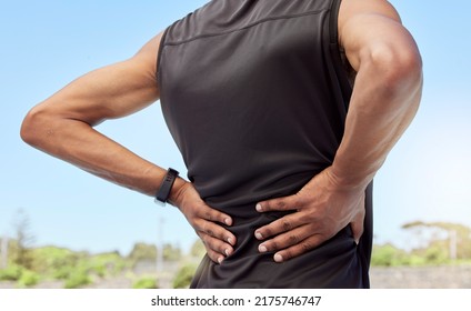 Rearview of athlete with back pain. Closeup back view of an uncomfortable young sportsman standing on a sport field holding his stiff and inflamed joints. Muscle or spinal strain due to injury - Shutterstock ID 2175746747