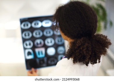 Rearview Of Ethnic Female Doctor Analyzing X-ray Or MRI Scan While Working In Hospital, Selective Focus. Physician Looking At CT Screening, Using Diagnostic Tool For Detecting Lung Diseases