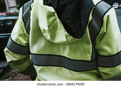 Rearview of a man in a high visibility jacket by the street