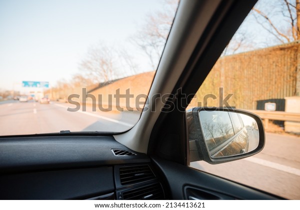Rearview mirror of a black\
car driving on a German autobahn. Safety and overtaking on fast\
highways 