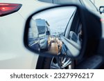 in the rearview mirror in the evening, cars with headlights are queuing in a traffic jam