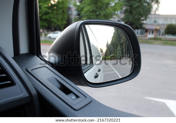 Rear-view mirror on a cargo van. Rearview\
mirror with reflection in it. Rear view mirror cargo van on the\
road. Wing mirror of a cargo van with nature\
street.